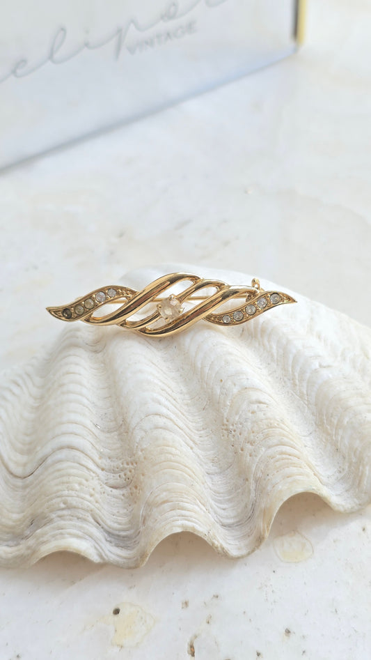 Vintažinė aukso spalvos sagė su stiklo kristalu bangelės