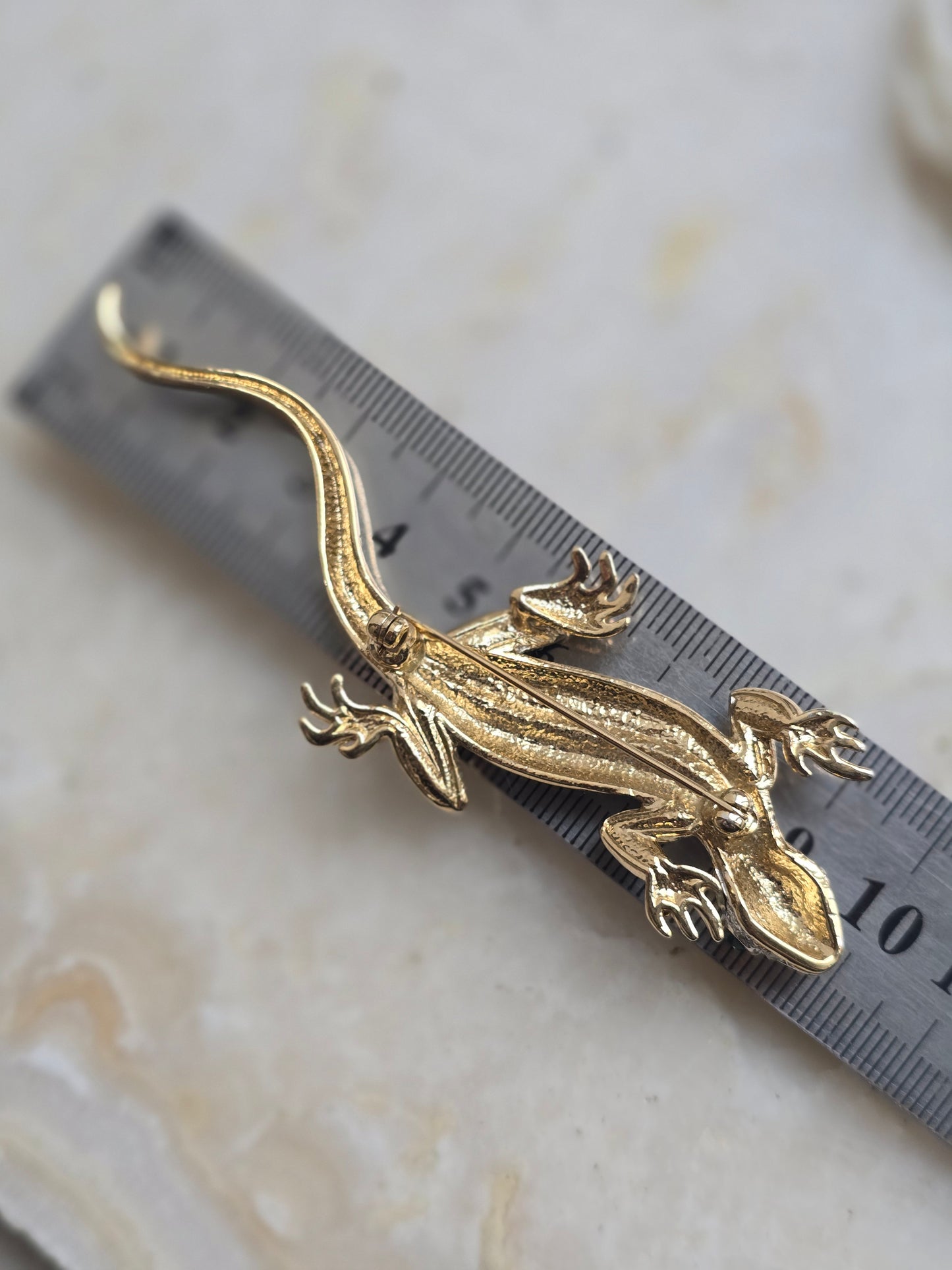 Aukso spalvos sagė su stiklo kristalais driežas